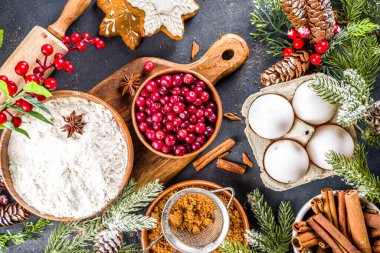 Noel yemeği, kış kurabiyesi, zencefilli çörek, meyveli kek, mevsimlik içecekler. Kızılcıklar, kurutulmuş portakallar, tarçın, baharatlar, koyu taş masadaki un, uzay manzarasını kopyala