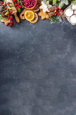 Noel yemeği, kış kurabiyesi, zencefilli çörek, meyveli kek, mevsimlik içecekler. Kızılcıklar, kurutulmuş portakallar, tarçın, baharatlar, koyu taş masadaki un, uzay manzarasını kopyala