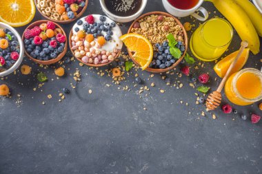 Çeşitli kahvaltı yemekleri konsepti. Geleneksel sağlıklı kahvaltı yemekleri ve içecekler - yulaf, granola, yoğurt, smoothie bowl, tost, mısır gevreği, kruvasan, kahve ve çay fincanı, portakal suyu, meyve, böğürtlen