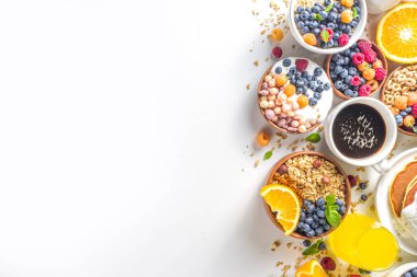 Çeşitli kahvaltı yemekleri konsepti. Geleneksel sağlıklı kahvaltı yemekleri ve içecekler - yulaf, granola, yoğurt, smoothie bowl, tost, mısır gevreği, kruvasan, kahve ve çay fincanı, portakal suyu, meyve, böğürtlen