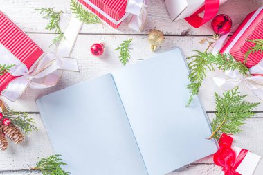 Not defterine noel süsü ve beyaz ahşap masada hediye kutuları olan bir kadın el yazısı. Noel dilek listesi, Noel Baba mektubu, liste konsepti, düz kopya alanı