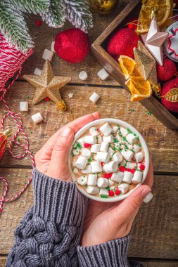Marşmelovlu sıcak çikolata, Noel kahvaltısı için sıcak çikolata, ahşap arka planda Noel süslemeleri, samimi kış fotoğrafı. Sıcak çikolata bardağı kızların elinde. 