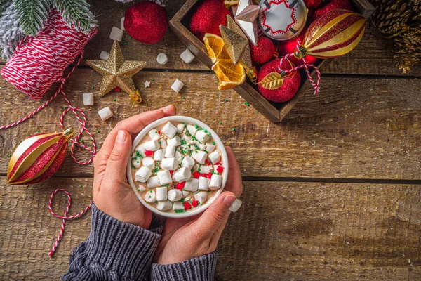 Marşmelovlu sıcak çikolata, Noel kahvaltısı için sıcak çikolata, ahşap arka planda Noel süslemeleri, samimi kış fotoğrafı. Sıcak çikolata bardağı kızların elinde. 