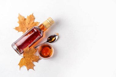 Şişe, kase ve kaşıkta akçaağaç yapraklı lezzetli akçaağaç şurubu, boşluğu kopyala.