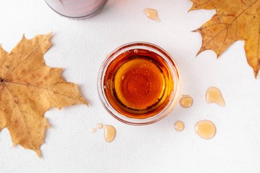 Şişe, kase ve kaşıkta akçaağaç yapraklı lezzetli akçaağaç şurubu, boşluğu kopyala.