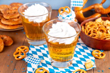 Oktoberfest tatlı fikri, üzerinde krem şanti olan renkli biralı iki bardak altın jöle pudingi, şenlikli Oktoberfest partisi ahşap masa, kopyalama alanı.