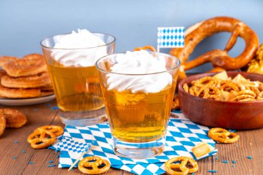 Oktoberfest tatlı fikri, üzerinde krem şanti olan renkli biralı iki bardak altın jöle pudingi, şenlikli Oktoberfest partisi ahşap masa, kopyalama alanı.