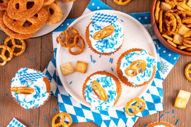 Oktoberfest kekleri tuzlu kraker, krem şanti ve renkli şeker serpintileri, beyaz ahşap arka planda Oktoberfest bayram dekoru, kopyalama alanı