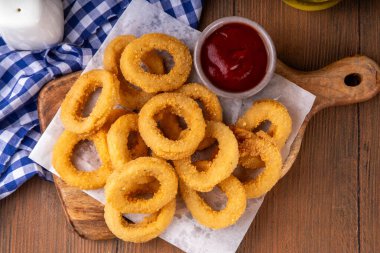 Ketçap soslu altın soğan halkaları, uçak fritözü beyaz ahşap masa fotokopi alanında lezzetli soğan halkaları atıştırmalıkları.
