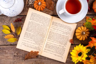 Sonbahar mevsiminde sıcak kahvaltı, bahçede erken sonbahar çayı, balkabağı mumları ve dekorlu taze demlenmiş çay fincanı, sonbahar yaprakları ve açık kitap, okuma zamanı sakin hayat