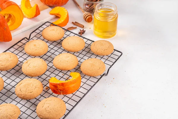 Ev yapımı Sonbahar Balkabağı Baharatlı Kurabiyeler fırında, tatlı sonbahar pişirme tatlı tarifi fikri, balkabağı kabağı ve baharatlar beyaz masada.