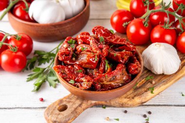 Zeytin yağında ev yapımı kurutulmuş domatesler, gurme İtalyan yemekleri, taze domates, yağ şişesi ve mutfak masasında baharatlar.