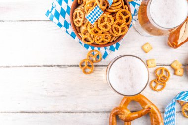 Oktoberfest tebrik kartı geçmişinde iki bira bardağı, tuzlu atıştırmalık ve kraker var. Oktoberfest barı, beyaz ahşap masa üzerindeki kafe menüsü, Ekim Festivali tarzı kareli peçete ve dekorla