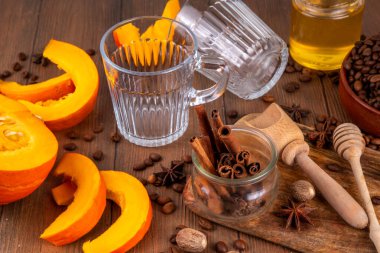 Balkabağı latte malzemeleri. Kabak kahvesi yapmak için temel malzemelerin seçimi: kabak, kahve çekirdekleri, baharatlar ve latte fincanları. Tahta bir masanın üstünde, manzaralı. Filtrelerle