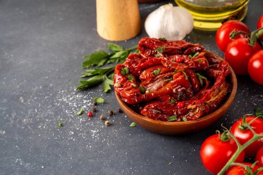 Zeytin yağında ev yapımı kurutulmuş domatesler, gurme İtalyan yemekleri, taze domates, yağ şişesi ve mutfak masasında baharatlar.