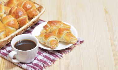 Bir tabakta, bir fincan kahve taze kruvasanlar