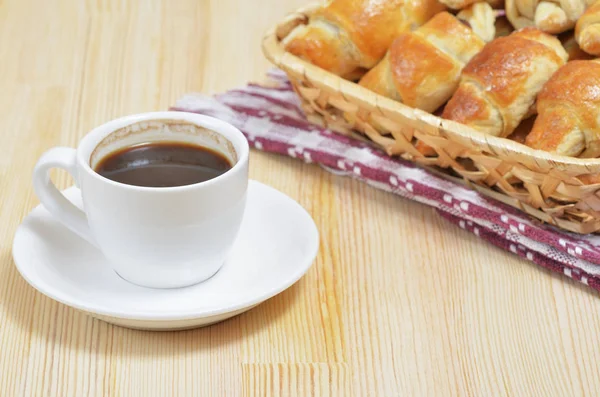 Yakınındaki bir fincan sıcak kahve masada bir hasır sepet yalanımı ev kruvasan freshened.