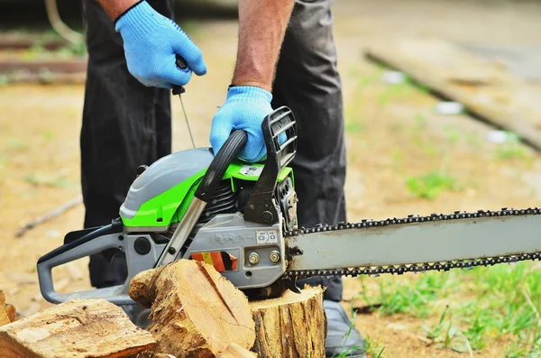 Eldiven bir erkekte bir günlük sprey bir chainsaw başlar