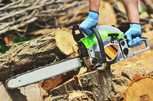 A man runs a chainsaw, removes a piece of wood