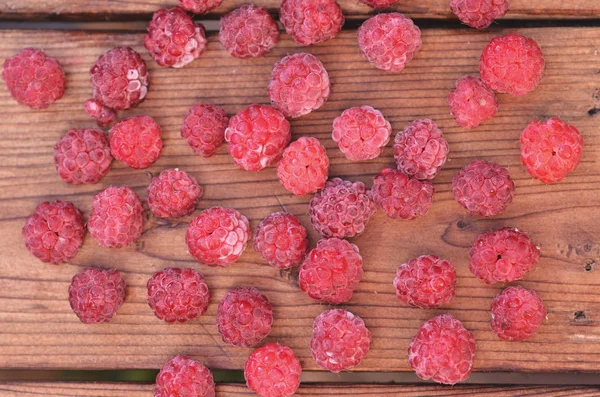 On a wooden background, raspberries are scattered, a photo from above — Stock Photo, Image