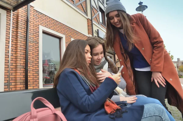 Üç kız sit tezgah ve telefon, resmi için yorum gülümseyen