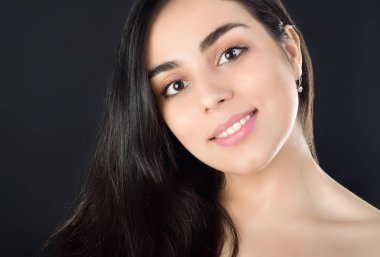Gülümseyen güzel bir esmer kızın portre fotoğrafı. Siyah arkaplanda stüdyo fotoğrafçılığı