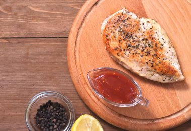 Baharatlı tavuk filetosu, bir tabak, baharat ve limonun yanında.