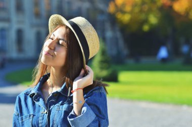 Şapkalı bir kot ceket giyen bir Asyalı kız güneş sahiptir