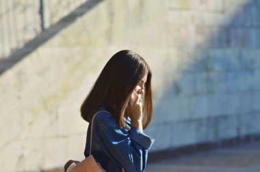 Genç bir kız telefonda konuşurken pembe bir sırt çantası ile şehir etrafında yürür