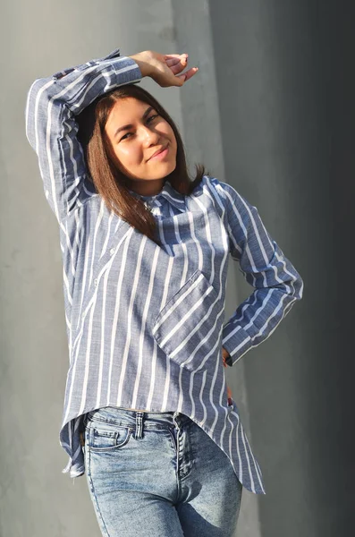 Jovem bela menina asiática fica perto da parede e posando e ela vestiu uma camisa listrada — Fotografia de Stock