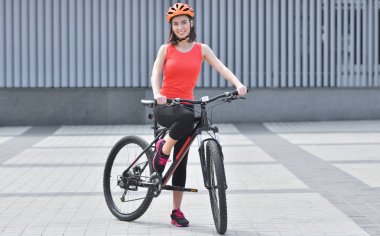 Kasklı eşofman giyen fit kız sokaklarda bisiklete biniyor.