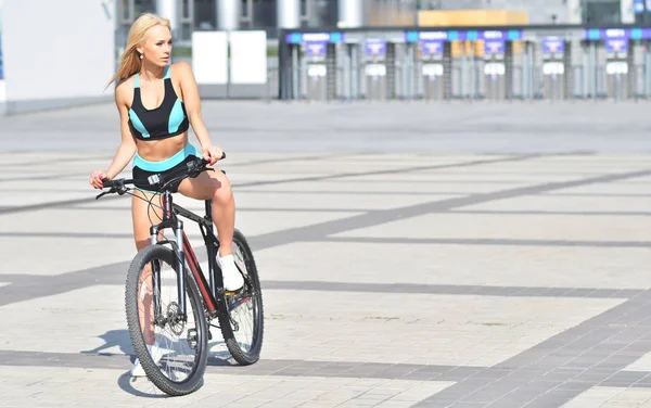 Sexy chica rubia en chándal montando una bicicleta — Foto de Stock