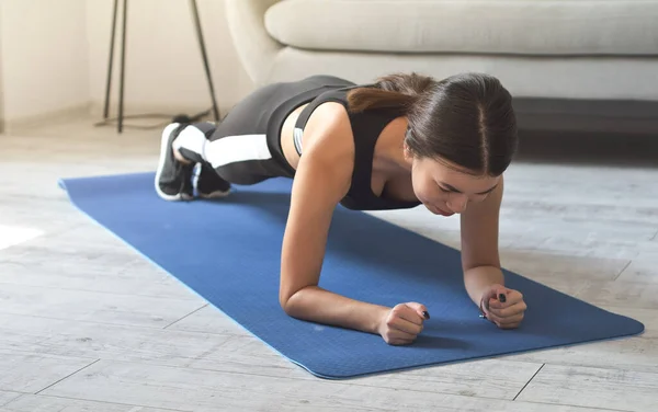 Atractiva chica delgada en ropa deportiva está haciendo ejercicios abdominales en el suelo Fotos de stock libres de derechos