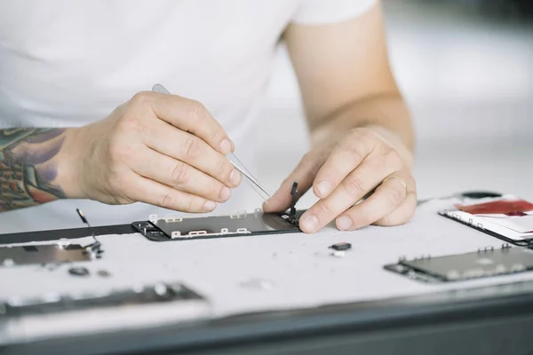 Electronics repair service. Technician disassembling smartphone for inspecting.