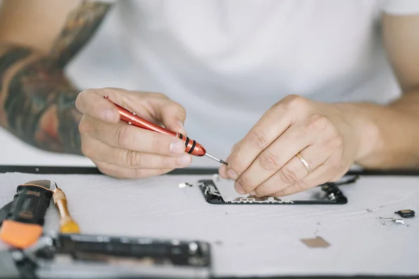 Electronics repair service. Technician disassembling smartphone for inspecting.