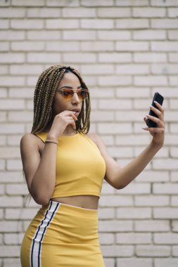 Hareket eden telefon ile poz Afro saçlı latin kadın.