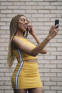 Hareket eden telefon ile poz Afro saçlı latin kadın.