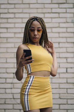 Hareket eden telefon ile poz Afro saçlı latin kadın.