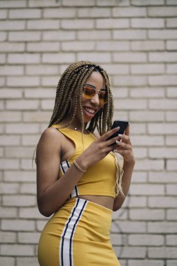 Hareket eden telefon ile poz Afro saçlı latin kadın.