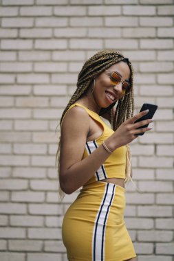 Hareket eden telefon ile poz Afro saçlı latin kadın.