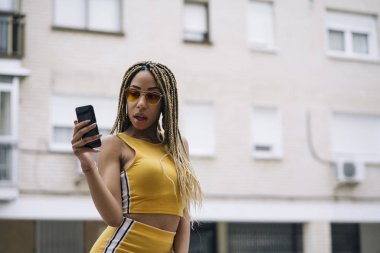 Hareket eden telefon ile poz Afro saçlı latin kadın.