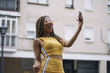 Hareket eden telefon ile poz Afro saçlı latin kadın.