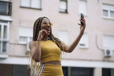 Hareket eden telefon ile poz Afro saçlı latin kadın.