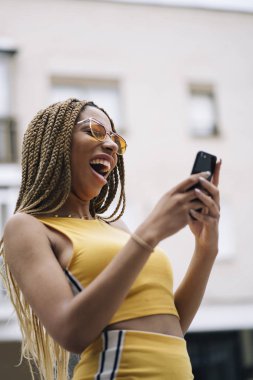 Hareket eden telefon ile poz Afro saçlı latin kadın.