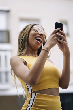 Hareket eden telefon ile poz Afro saçlı latin kadın.