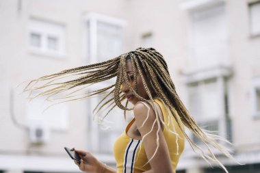 Hareket eden telefon ile poz Afro saçlı latin kadın.