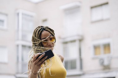 Hareket eden telefon ile poz Afro saçlı latin kadın.