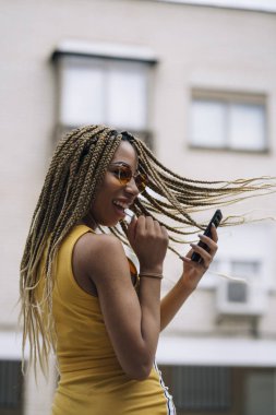 Hareket eden telefon ile poz Afro saçlı latin kadın.