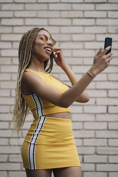 Hareket eden telefon ile poz Afro saçlı latin kadın.