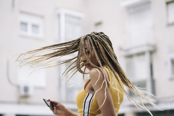 Hareket eden telefon ile poz Afro saçlı latin kadın.